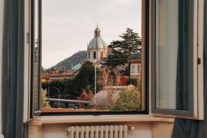 Vista desde una ventana que da a un edificio histórico con cúpula, rodeado de árboles y otros edificios.