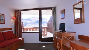 Une chambre d’hôtel avec un balcon, un lit, un bureau et une télévision.