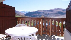 Un balcon avec une balustrade en bois, une table blanche et deux chaises blanches.