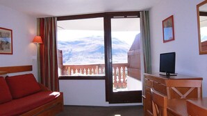 Habitació d'hotel amb balcó, llit, escriptori i televisió.