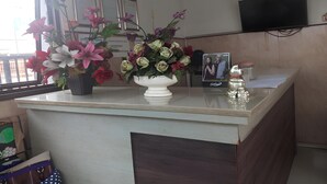 A reception desk with a vase of flowers, a framed photo, and a Coca-Cola can. - Hotel Orchid Syariah (Tegal)