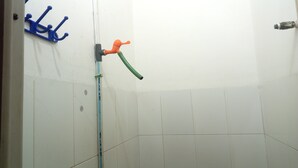 A bathroom with white tiled walls, a blue towel rack, and a green and orange faucet. - Wisma Pelita Syariah Tegal (Tegal)