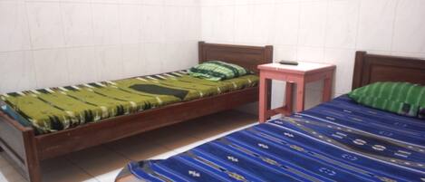 Una habitación con dos camas de madera, cada una con un edredón de estampado diferente.