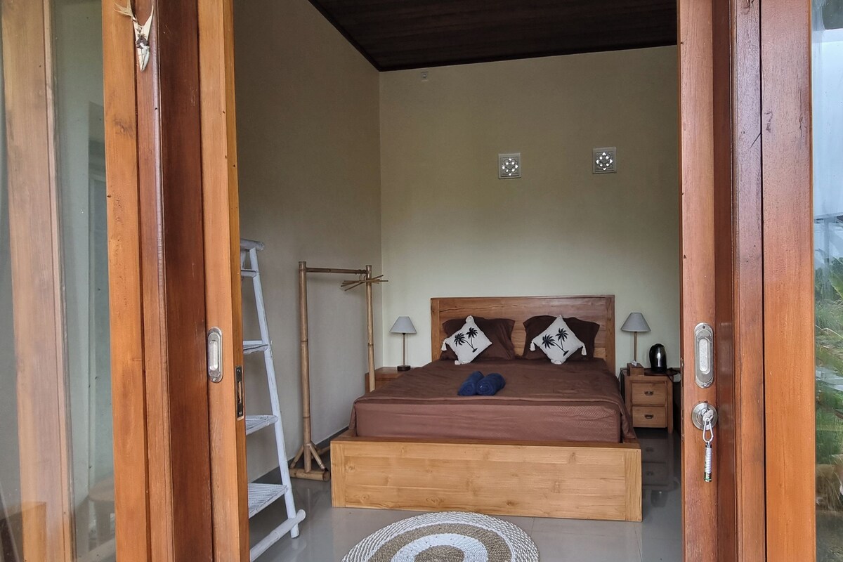 A bedroom with a wooden bed, a nightstand, a lamp, and a ladder.