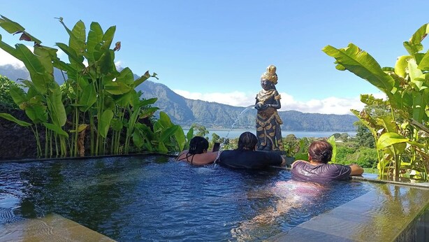 Une piscine à débordement offrant une vue sur les montagnes et une statue.