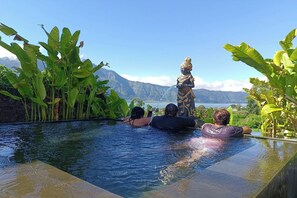 A infinity pool with a view of mountains and a statue. - Onion Garden And Natural Hotspring (Kintamani)