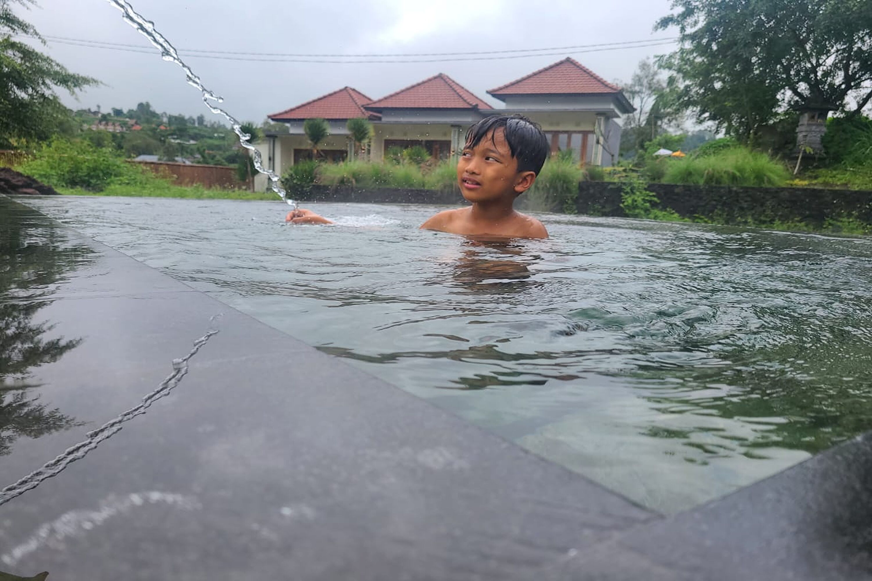 A person in a swimming pool with a house in the background.