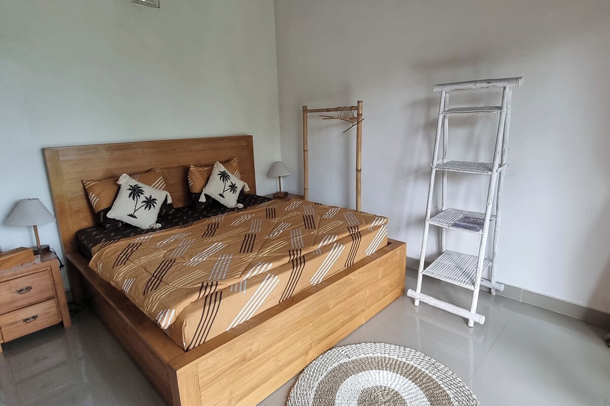 A neatly arranged bedroom with a wooden bed, bedside tables, a lamp, and a white shelving unit.