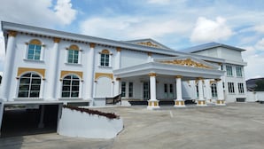 A large, white building with golden accents and columns, featuring a covered entrance and a spacious driveway. - Maulidia Hotel Syariah & Convention Center (Jambi)