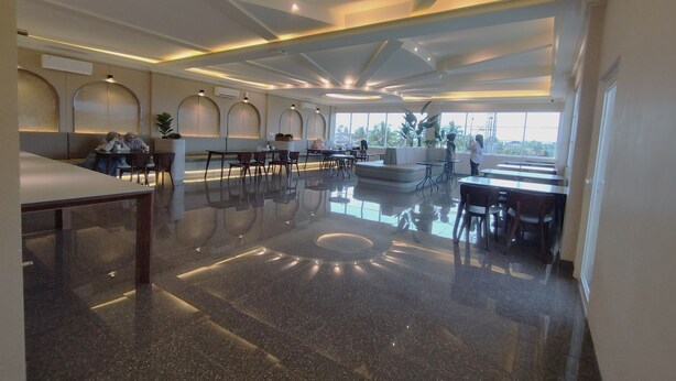 A spacious, modern hotel lobby with a polished marble floor, contemporary furniture, and large windows offering a view of the outdoors. - Maulidia Hotel Syariah & Convention Center (Jambi)