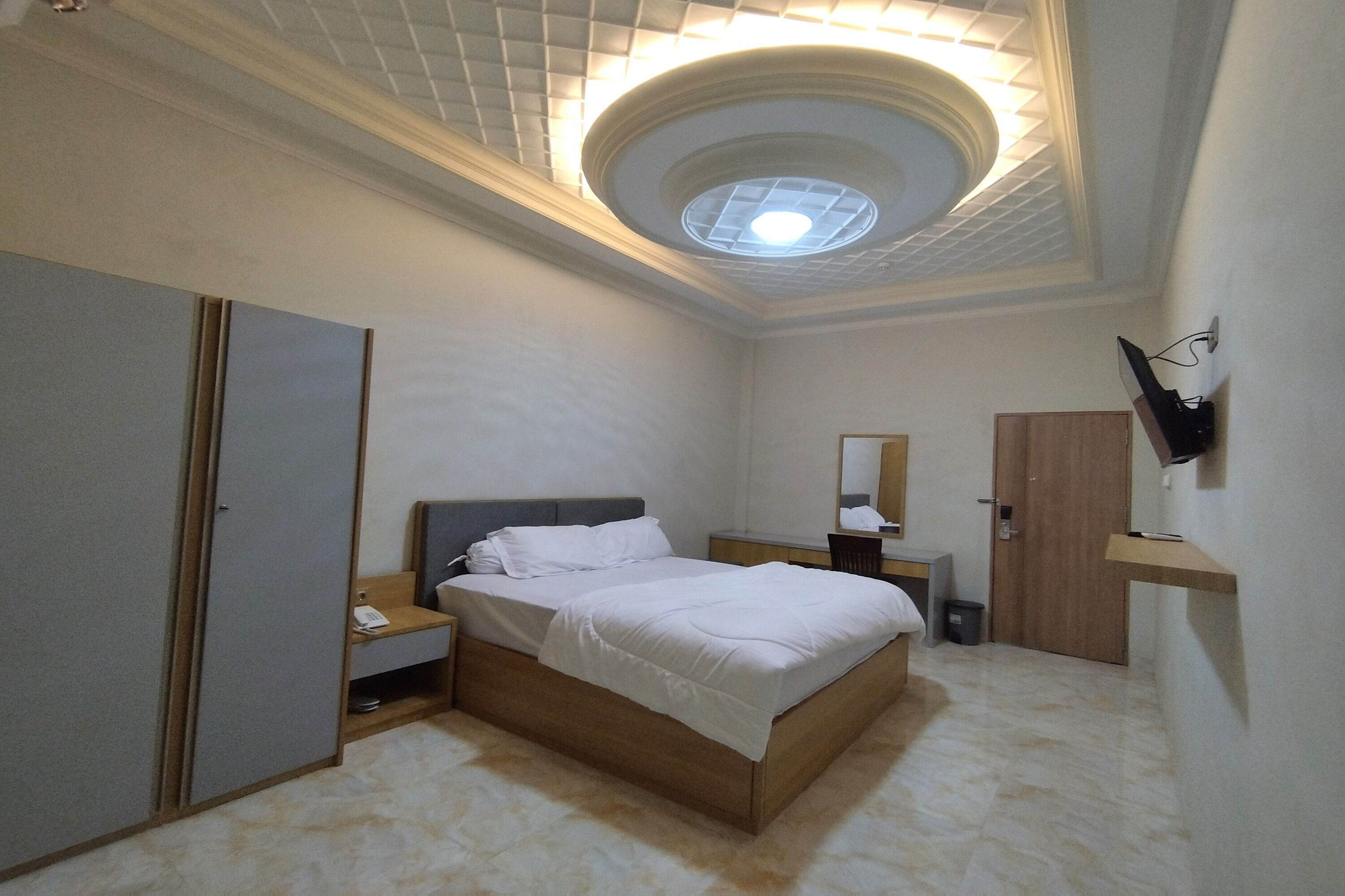 Una camera da letto con un letto, un armadio, una scrivania, uno specchio e una lampada a soffitto.