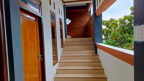 A staircase with wooden steps and white walls, leading to a wooden door. - Penginapan Bromo Lovero (Sukapura)