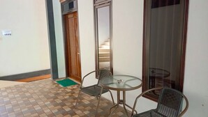 A small room with a tiled floor, a round glass table, two chairs, and a wooden door. - Penginapan Bromo Lovero (Sukapura)