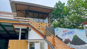 A building with a staircase, a security sign, and a mural of a volcano. - Penginapan Bromo Lovero (Sukapura)