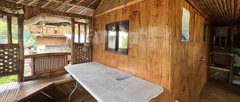 Una cabaña de madera con una mesa, bancos, una ventana y una terraza de madera.