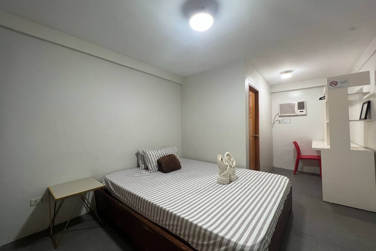 A small, clean room with a single bed, a desk, and a chair.