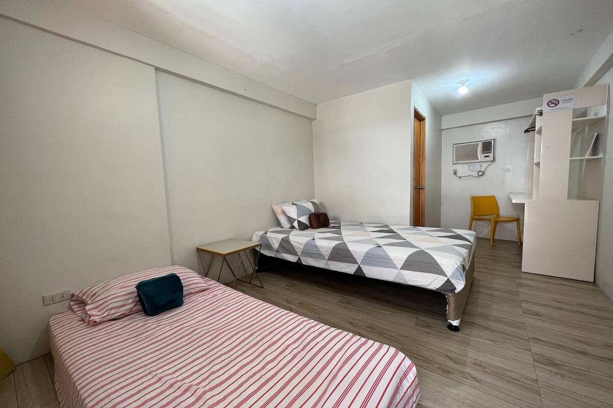 A bedroom with two beds, a desk, and a chair.