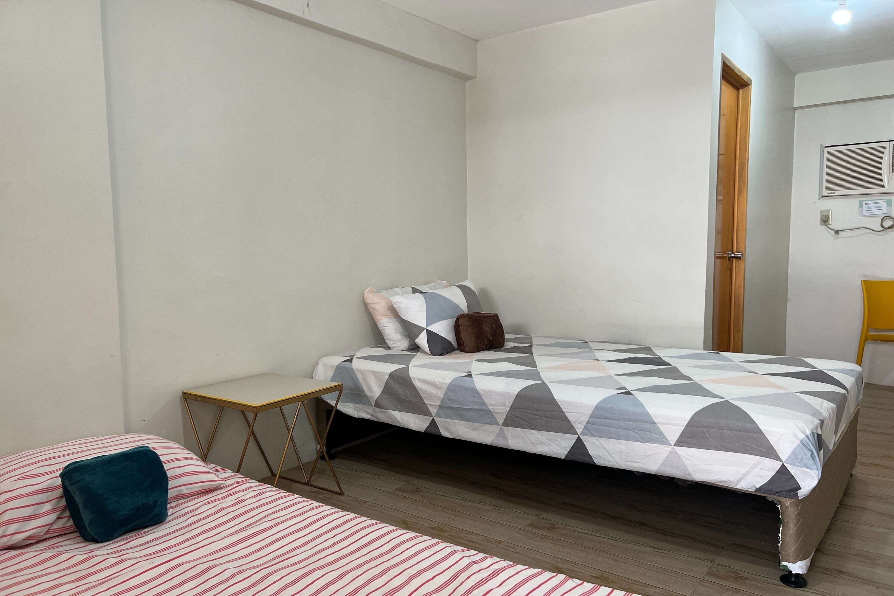 A bedroom with a bed, a small bedside table, a chair, and a wooden floor.