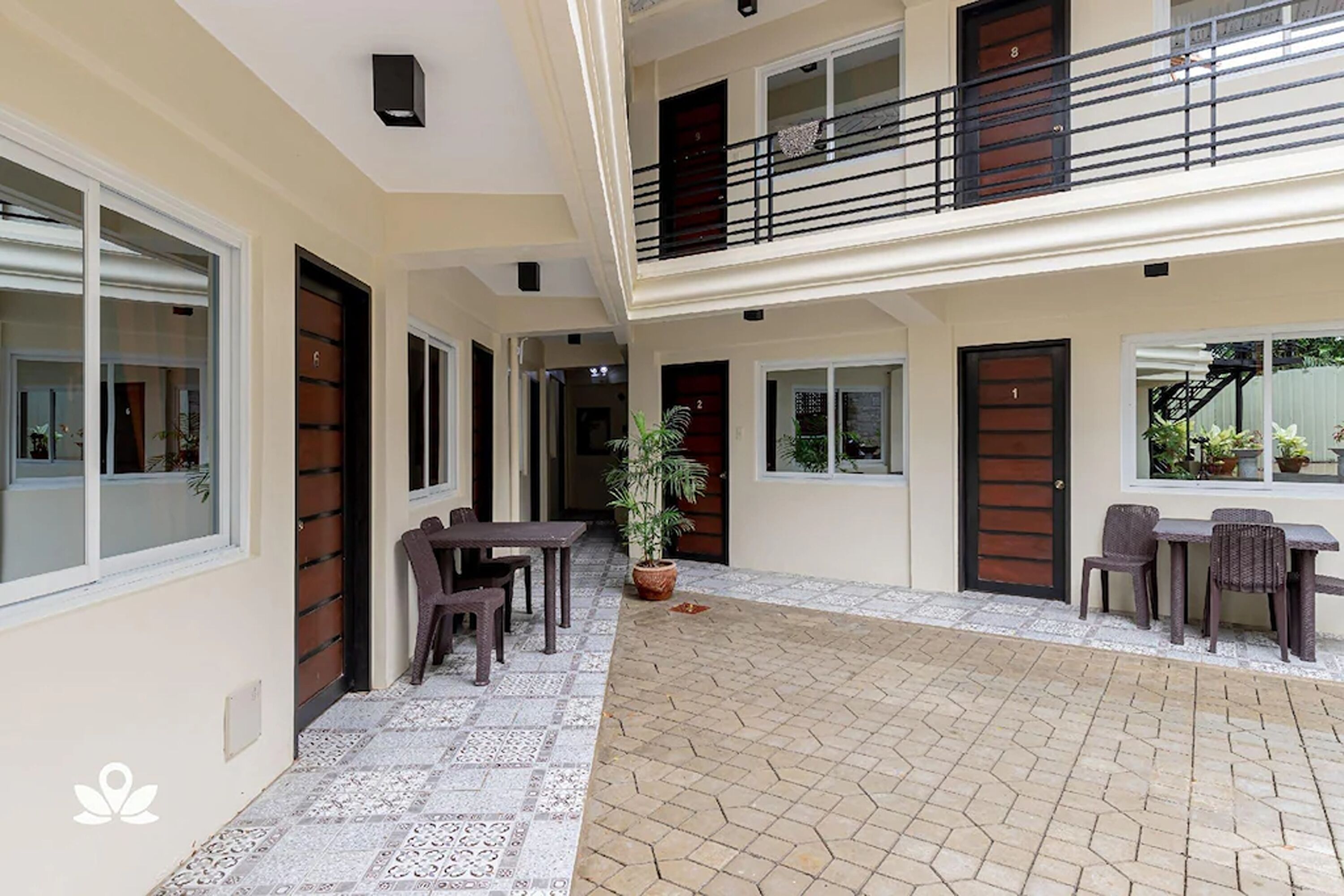 Un edificio residencial de varios niveles con un patio cubierto, mobiliario exterior y plantas en macetas.