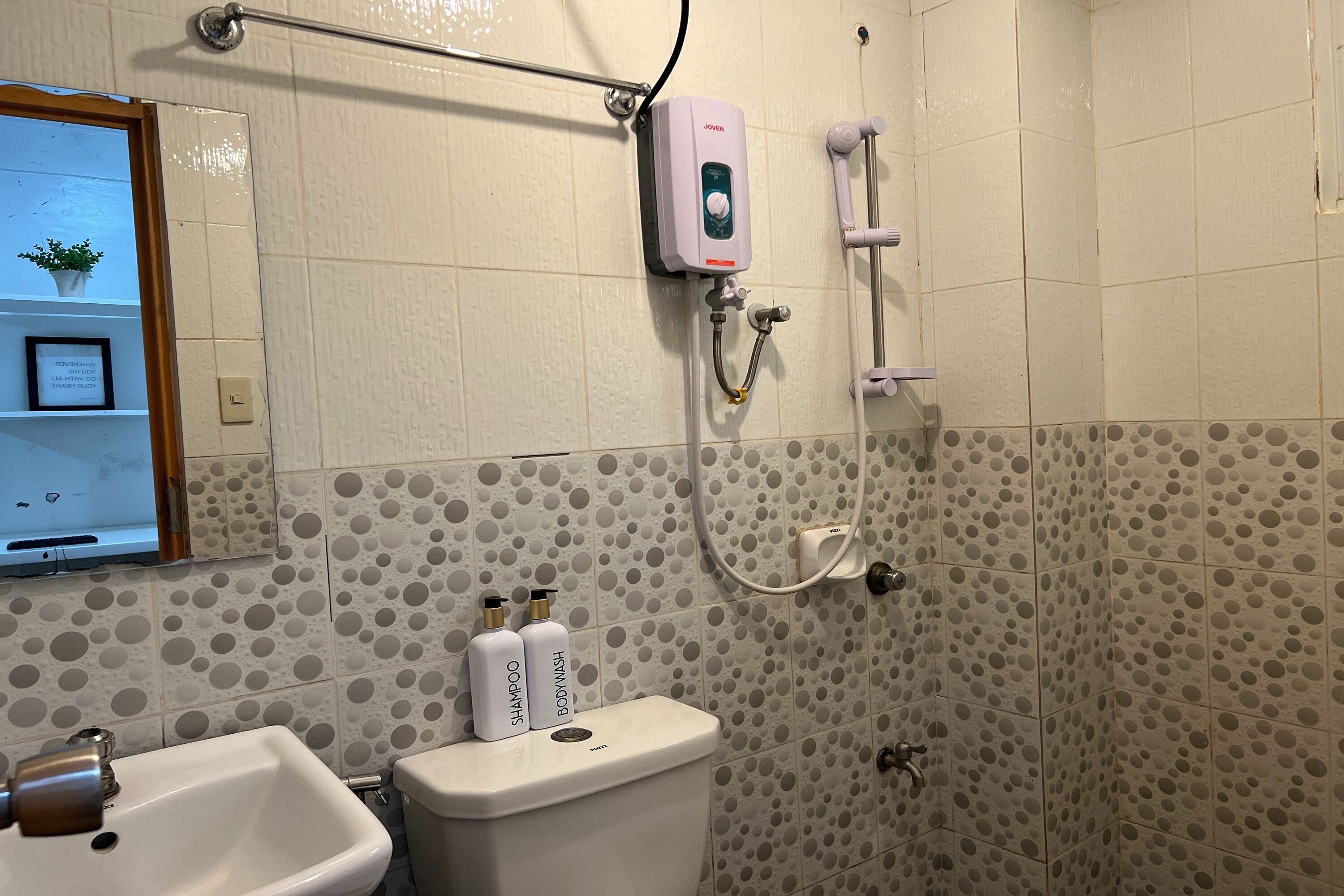 Een badkamer met toilet, wastafel, douche en handdoekhouder.