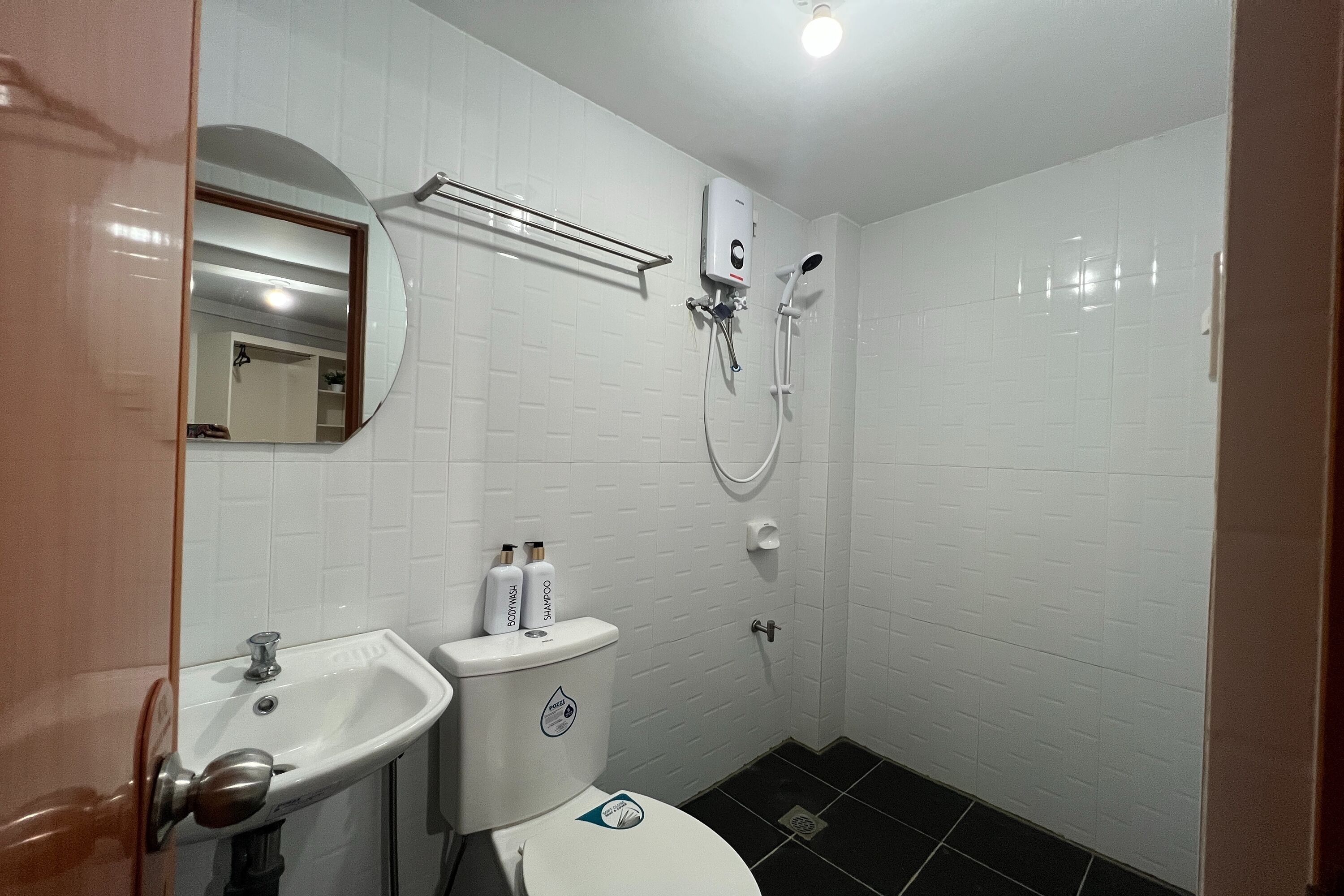 A bathroom with a sink, mirror, toilet, and shower.