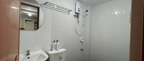 A bathroom with a sink, mirror, toilet, and shower.