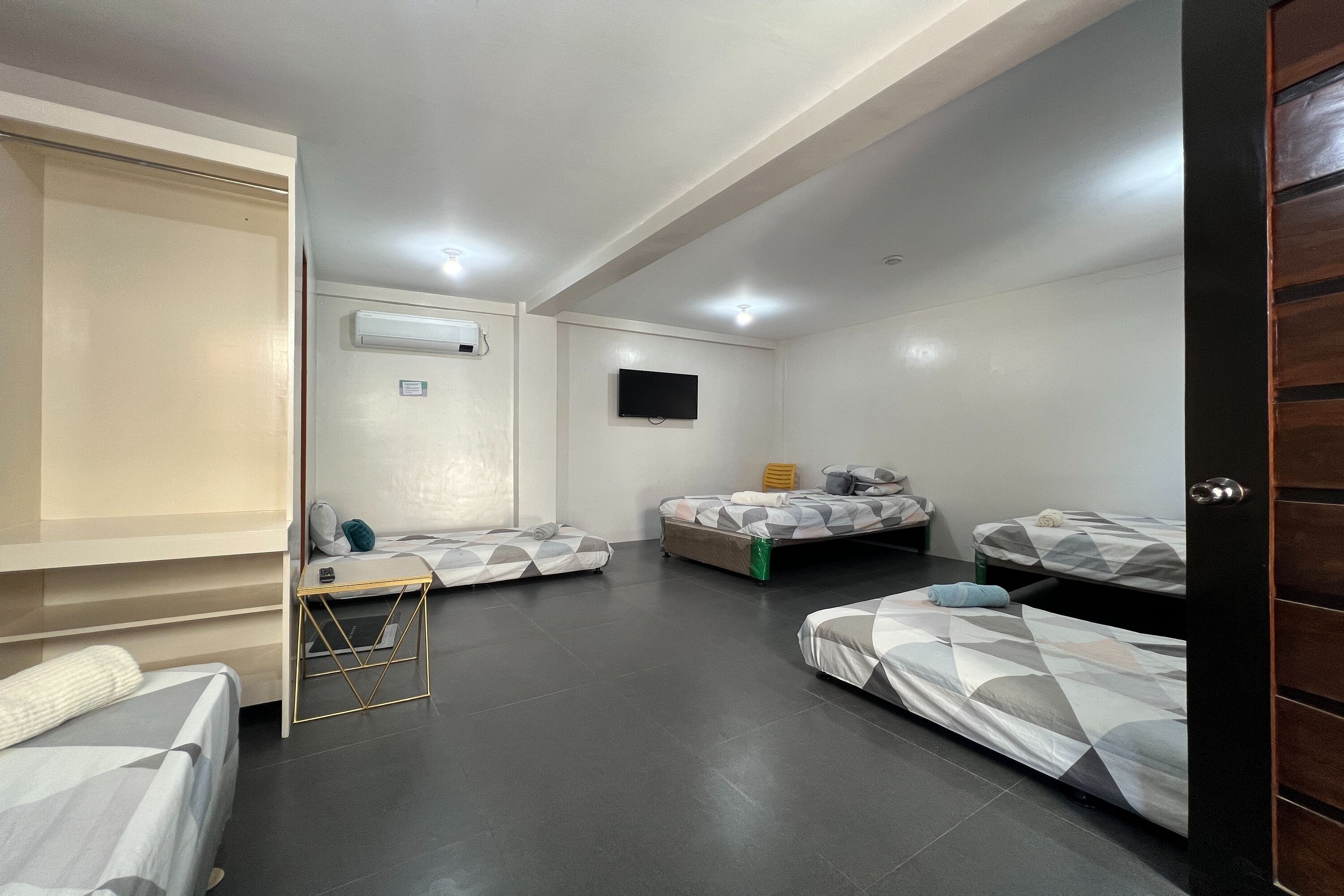 A room with three beds, a desk, and a television.
