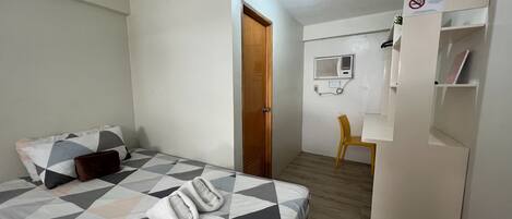 Una habitación de hotel con una cama, un escritorio, una silla, un armario y una puerta.