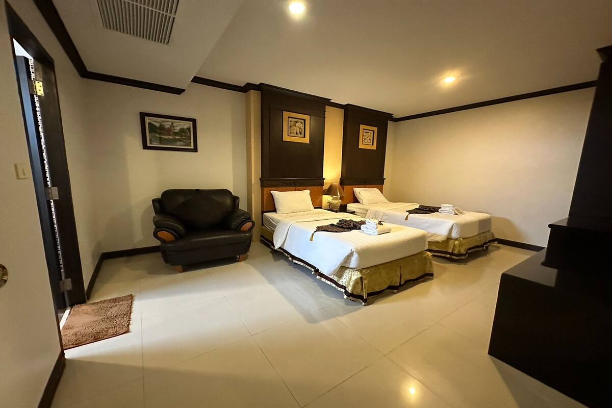 A hotel room with two beds, a chair, and a desk.
