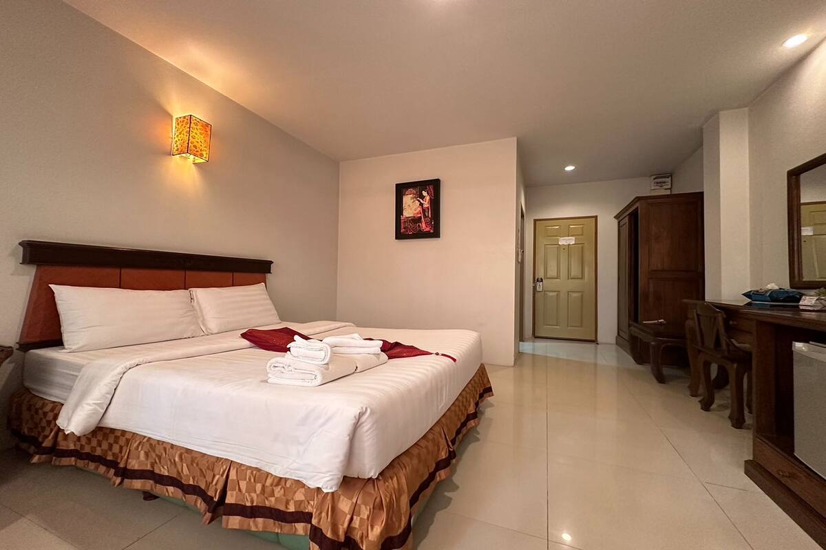A hotel room with a large bed, a desk, and a chair.