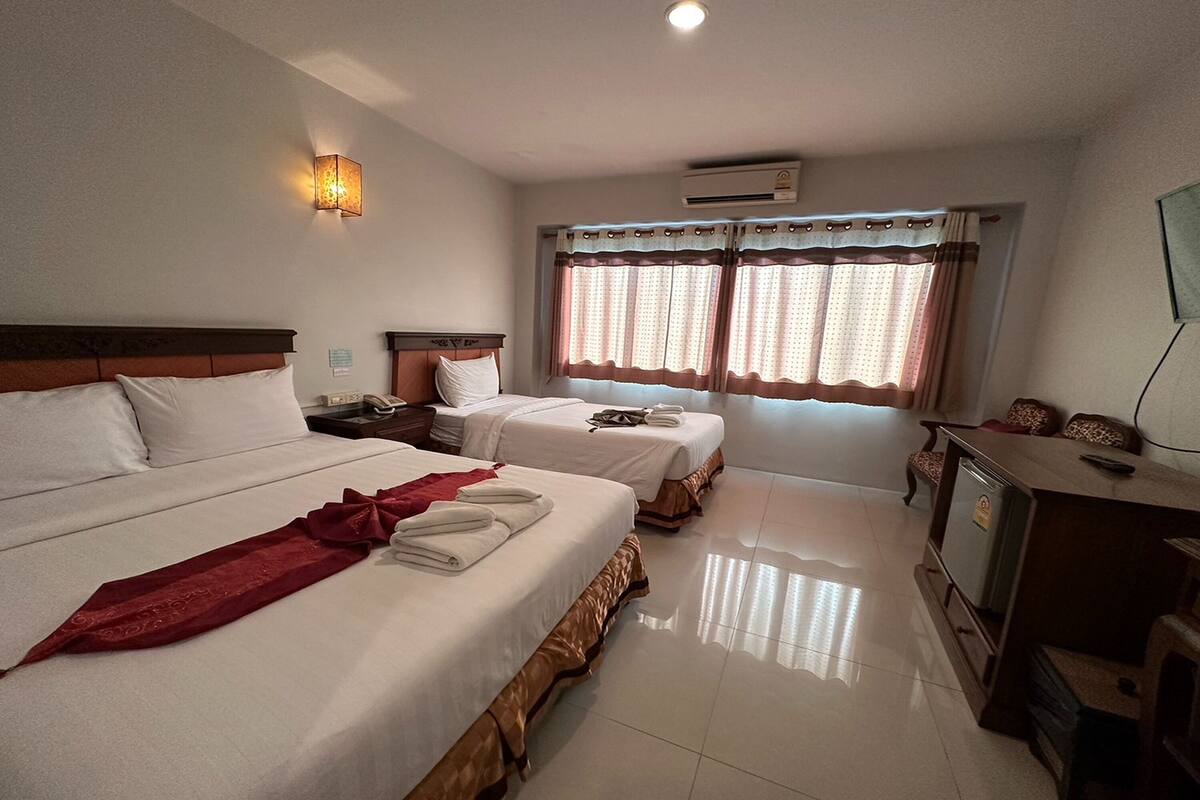 A hotel room with two beds, a TV, and a desk.