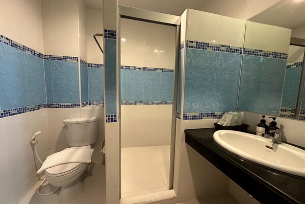 A bathroom with a toilet, shower, and sink.