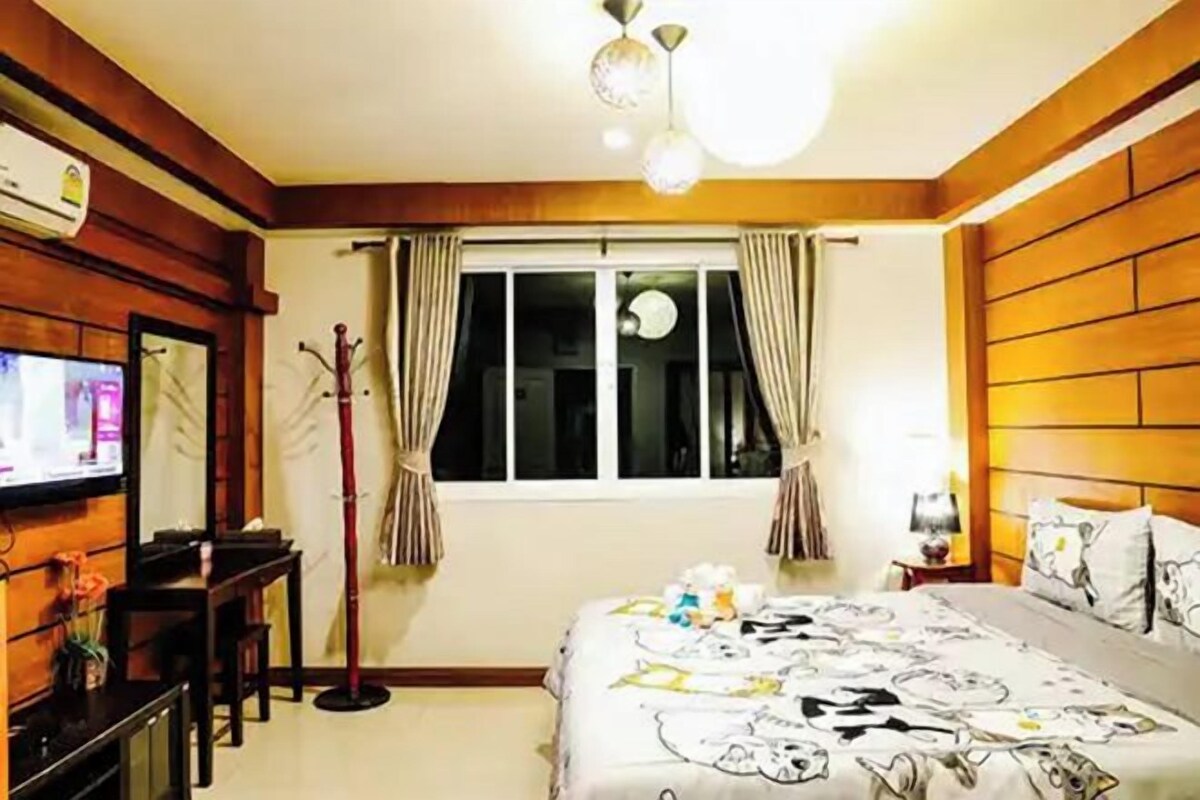 A hotel room with a bed, a television, a desk, and a window with curtains.