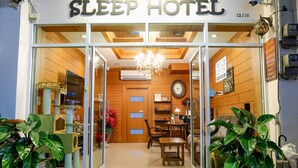 The entrance of a Sleep Hotel with a wooden interior, a chandelier, and a clock on the wall. - Sleep Hotel (Chonburi)