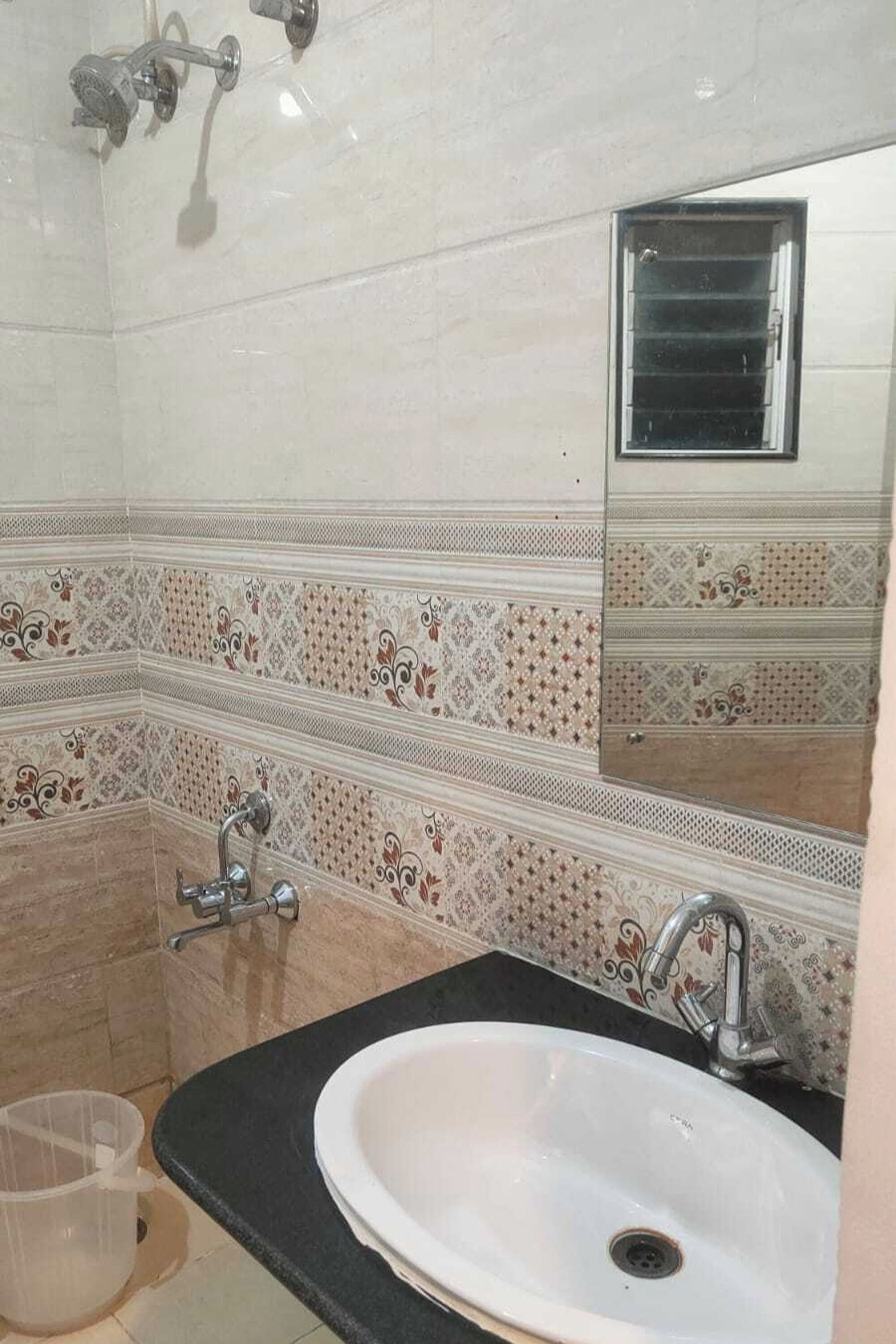Een badkamer met een wit wastafelmeubel, een zwart aanrechtblad en betegelde vloeren.