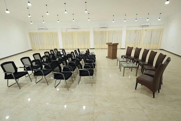 A conference room with rows of chairs, a podium, and ceiling lights.