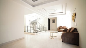 Amplia sala de estar con una escalera, un sofá marrón y una mesa de centro redonda.