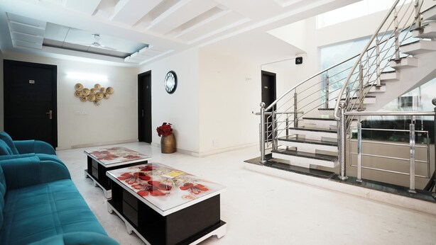 Una sala de estar moderna con un sofá, una mesa de centro y una escalera con barandillas de metal.