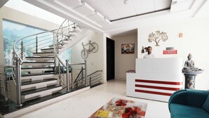 Un vestíbulo de hotel moderno con una escalera espiral, un mostrador de recepción y una estatua decorativa.