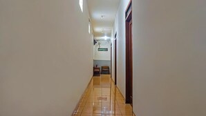Un corridoio con pavimento piastrellato, pareti bianche e una ventola a soffitto.