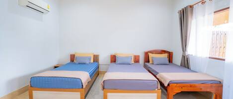 A room with three wooden beds, a white air conditioner, and a window with curtains.
