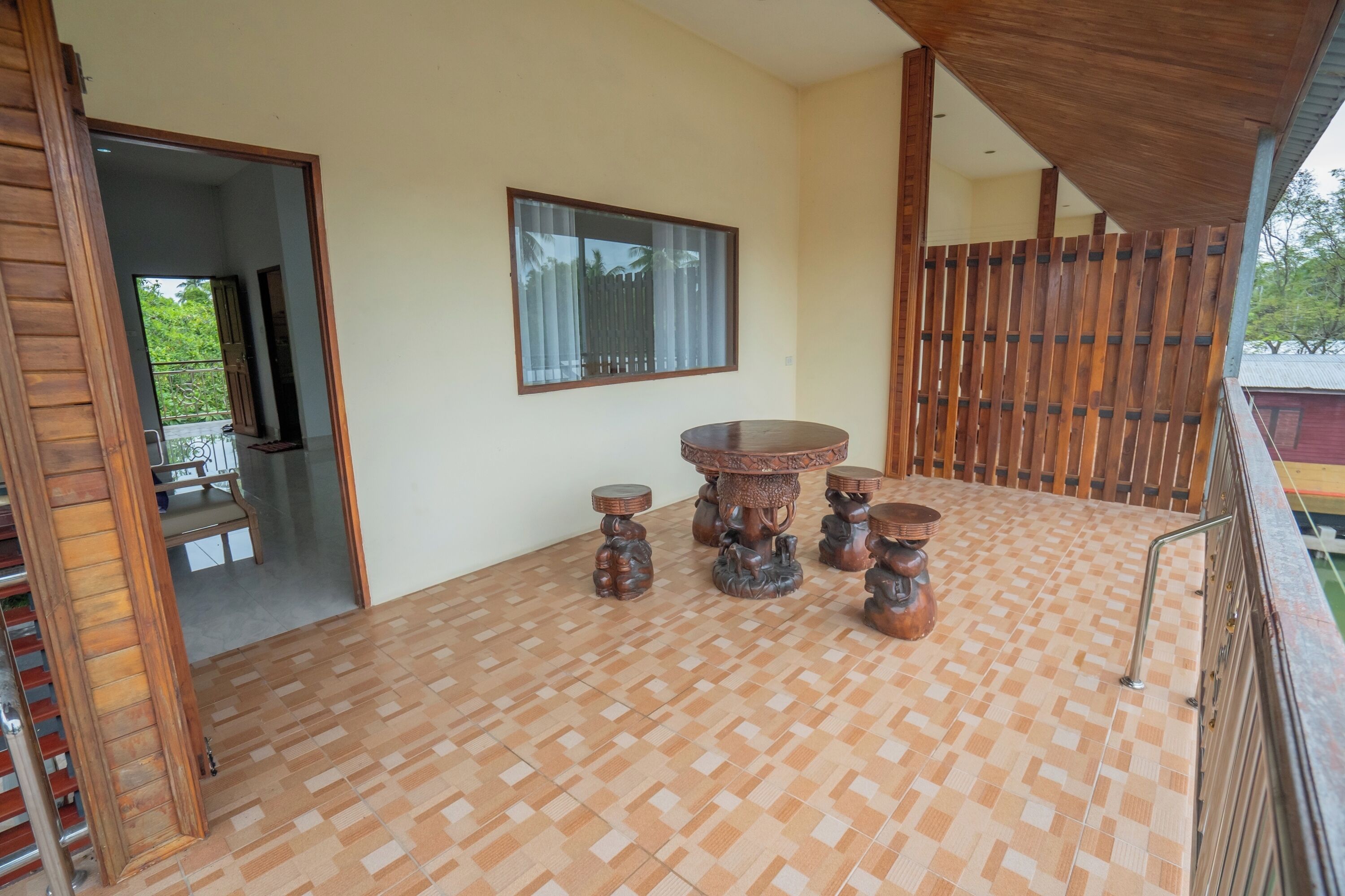 A room with a checkered floor, a round wooden table with four legs, and a window with curtains.