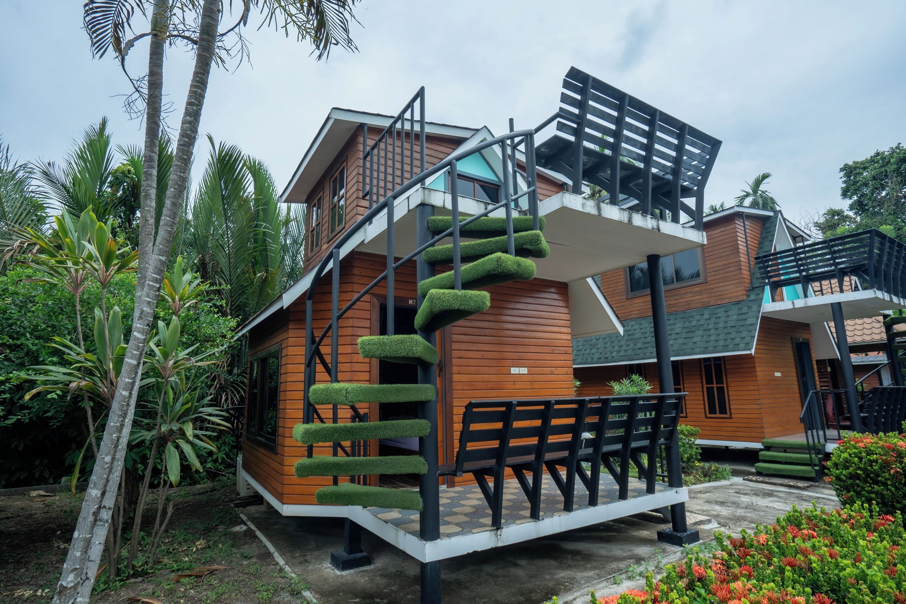 Un bâtiment moderne doté d’un escalier en colimaçon, d’une façade en bois et d’un balcon avec un banc.