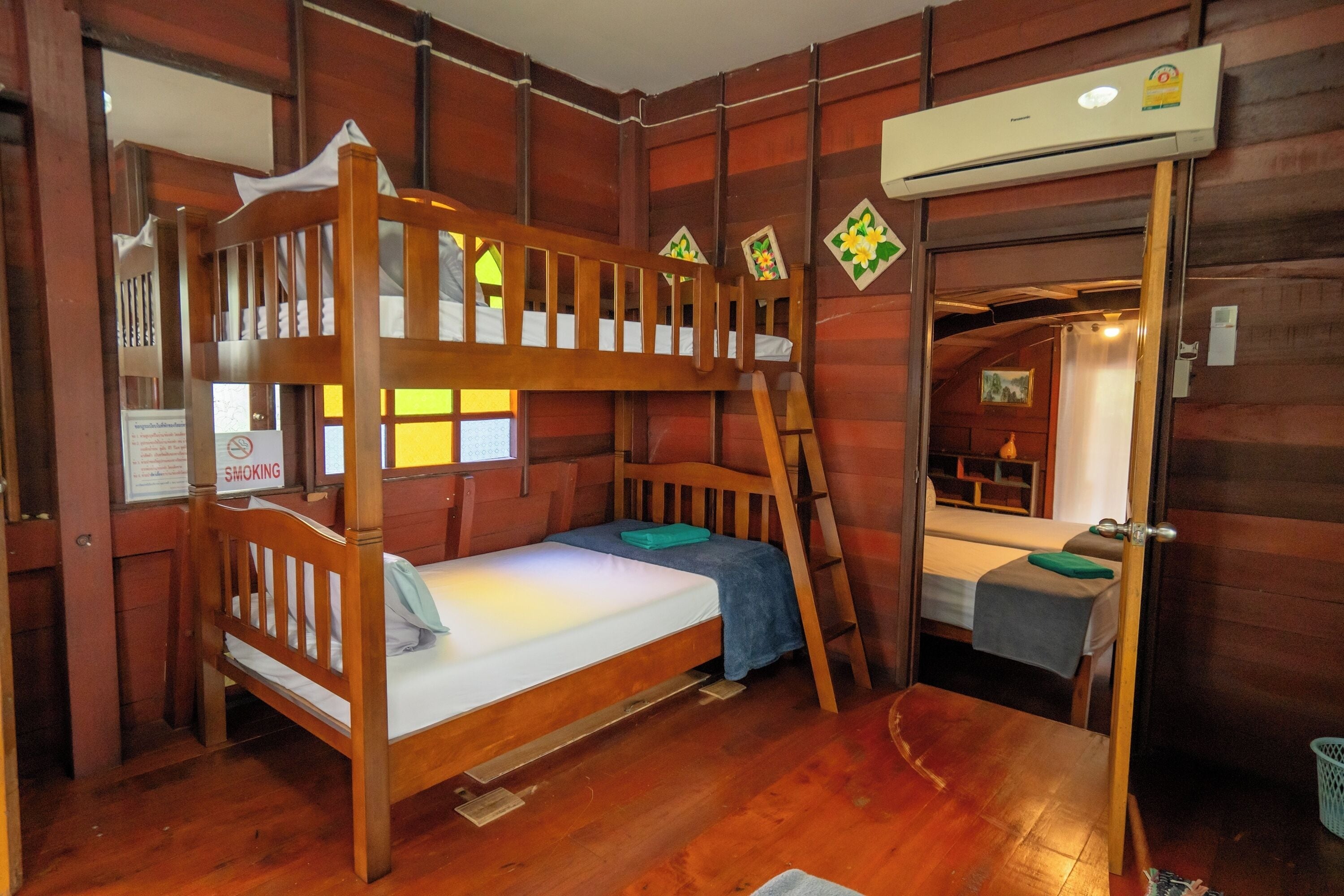 A bunk bed room with a wooden floor, a desk, and an air conditioning unit.