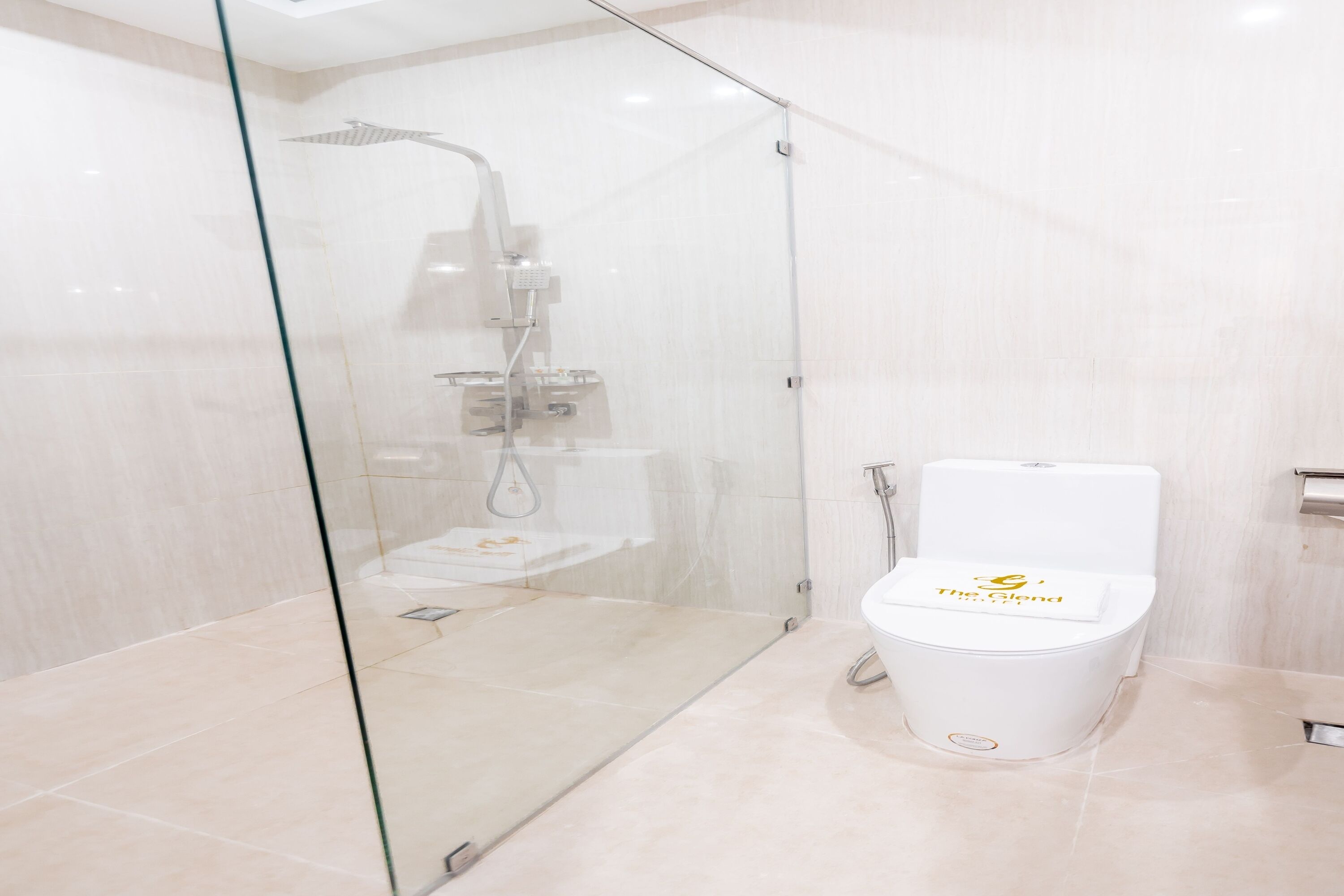 A modern bathroom with a glass-enclosed shower, a white toilet, and a glass partition.