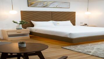 Un dormitorio moderno con una cama grande, cabecera de madera, mesitas de noche, una mesa redonda y una pequeña planta en maceta.
