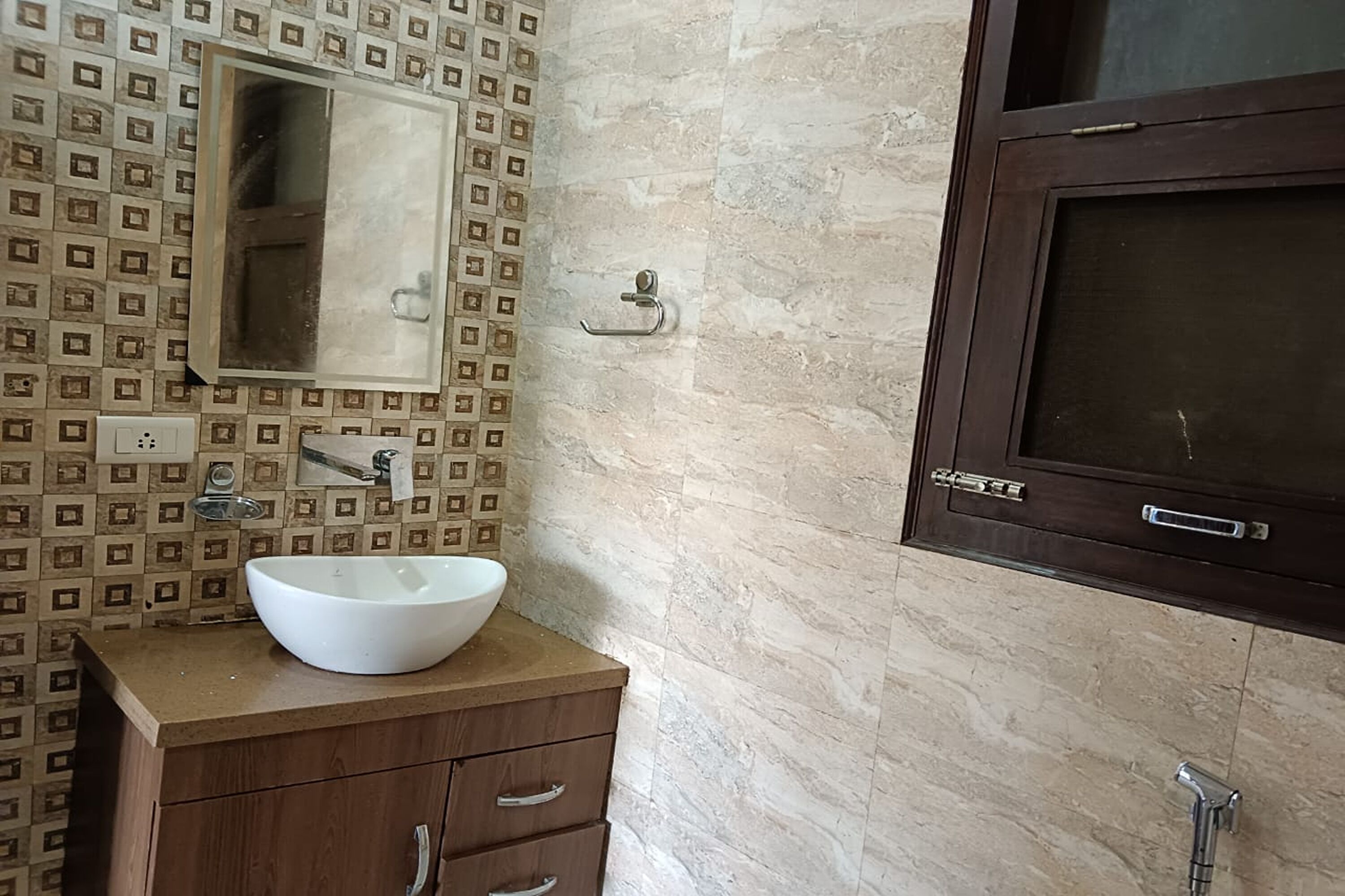 Un baño con lavamanos blanco, tocador de madera, salpicadero de azulejos y espejo.