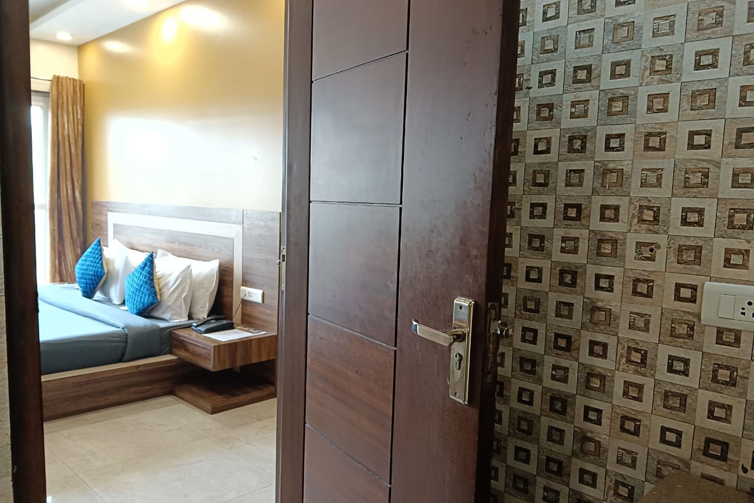 A bedroom with a bed, nightstand, and a door leading to another room.
