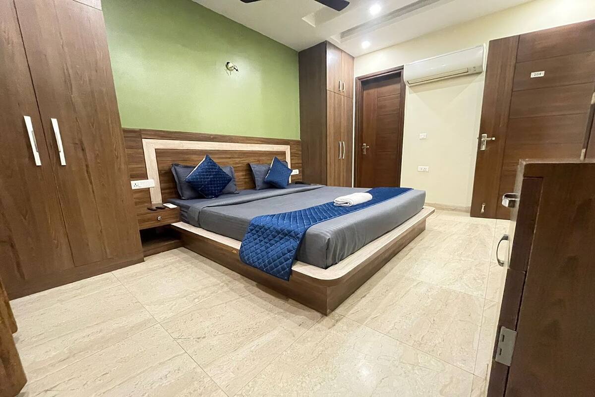 A bedroom with a bed, wooden wardrobe, and a green wall.