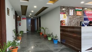 A hotel reception area with a polished marble floor, potted plants, and a reception desk. - The Indian Hotel & Kitchen (Gurugram)